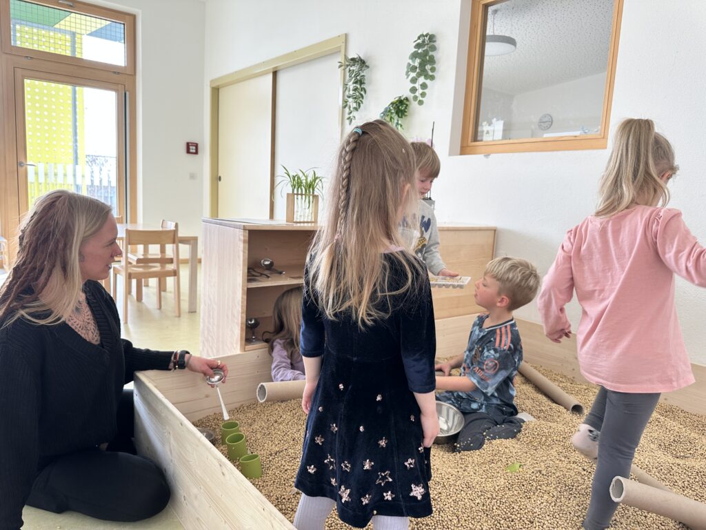 Kinder der städtischen Kita Schneckenhaus spielen im neuen Bohnenbad. Einem Spielplatz gefüllt mit Sojabohnen. 