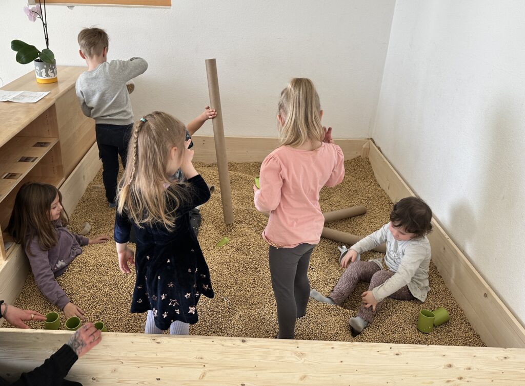 Kinder der städtischen Kita Schneckenhaus spielen im neuen Bohnenbad. Einem Spielplatz gefüllt mit Sojabohnen. 
